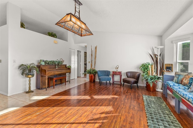 sitting room with a textured ceiling, lofted ceiling, and hardwood / wood-style floors