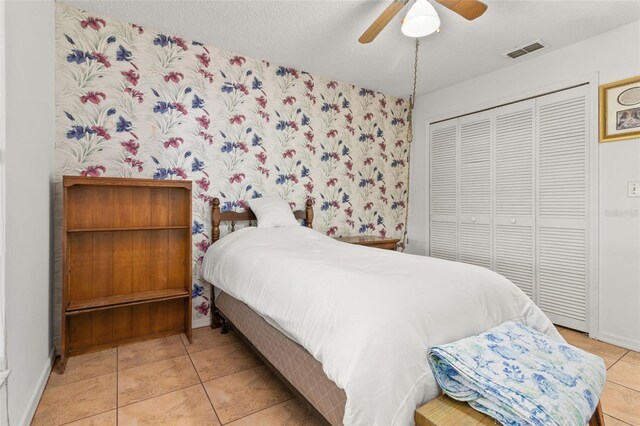 bedroom with a closet, ceiling fan, a textured ceiling, and light tile patterned flooring