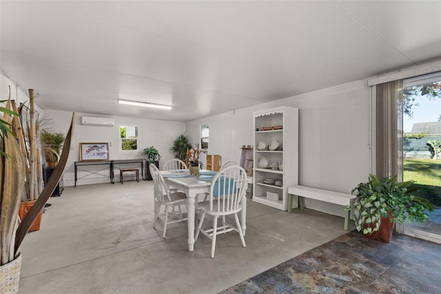 dining space featuring a wall unit AC and concrete flooring