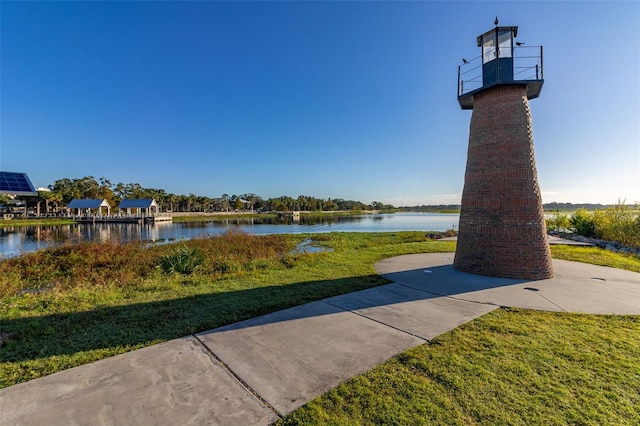 view of home's community with a water view and a lawn