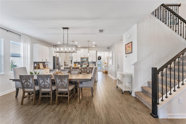 dining area featuring a textured ceiling, a chandelier, and wood-type flooring