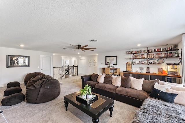 living room featuring a textured ceiling, light colored carpet, and ceiling fan