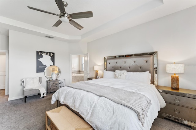 carpeted bedroom featuring ensuite bathroom, a tray ceiling, and ceiling fan