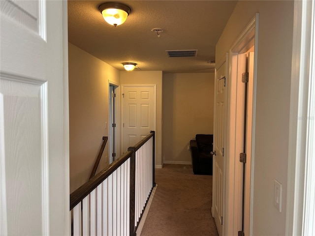 hallway featuring carpet and a textured ceiling