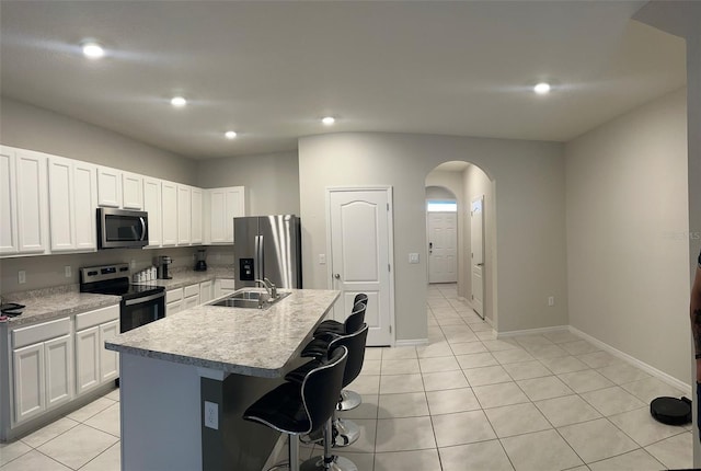 kitchen featuring white cabinets, appliances with stainless steel finishes, a kitchen breakfast bar, a kitchen island with sink, and sink