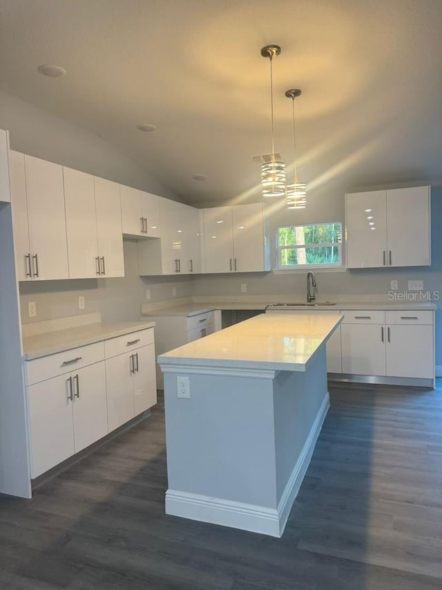 kitchen with white cabinets, decorative light fixtures, dark hardwood / wood-style flooring, and vaulted ceiling