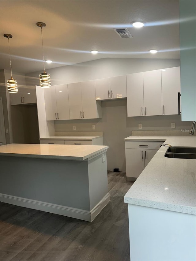 kitchen with dark hardwood / wood-style floors, sink, white cabinetry, and hanging light fixtures