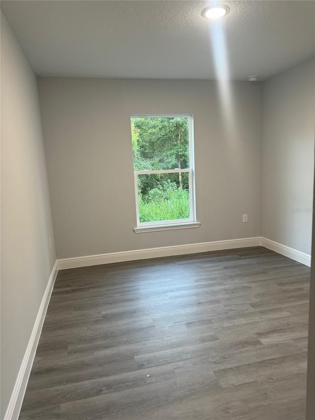 spare room featuring dark hardwood / wood-style flooring and a textured ceiling