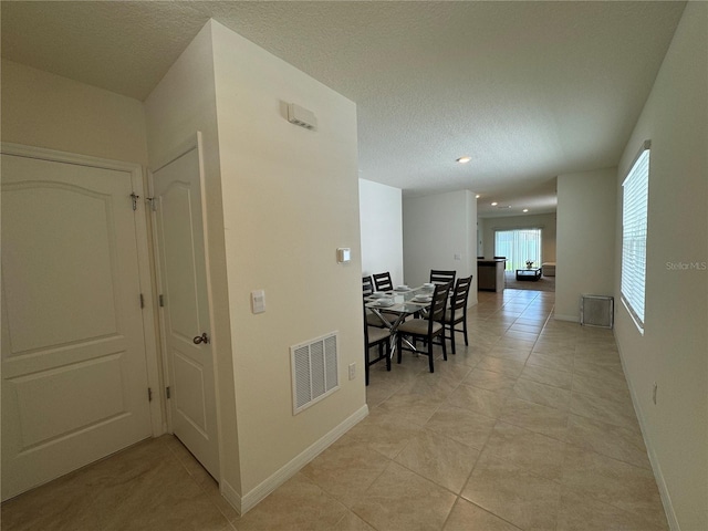 corridor with a textured ceiling and light tile patterned floors