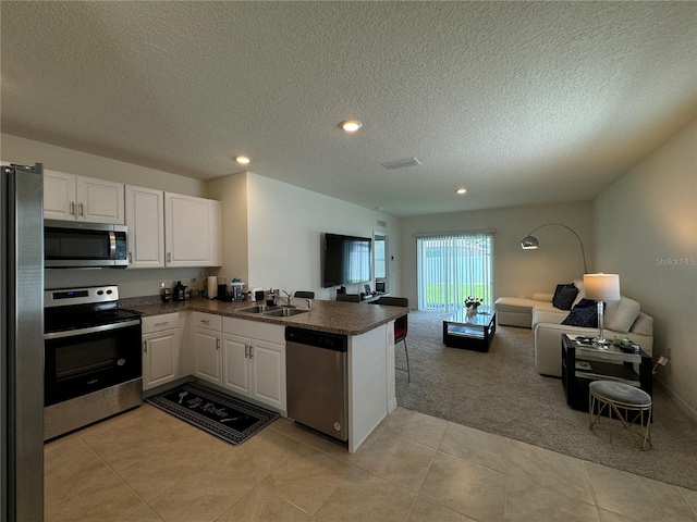 kitchen featuring light carpet, kitchen peninsula, white cabinetry, appliances with stainless steel finishes, and a textured ceiling