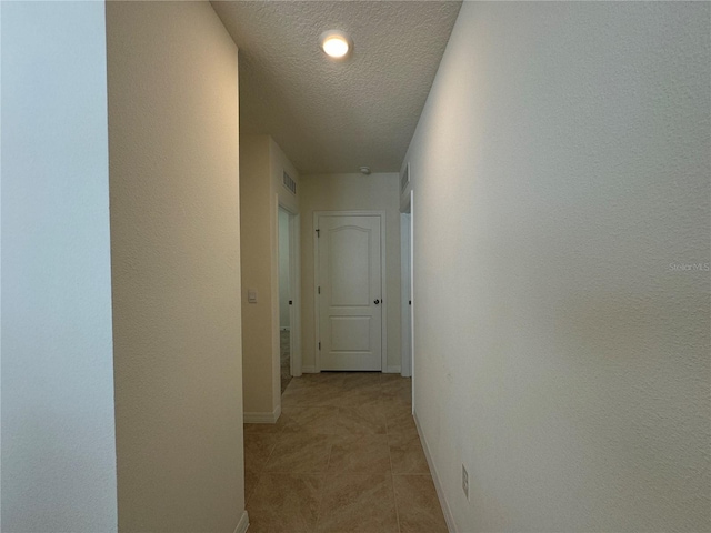 hallway featuring a textured ceiling and light tile patterned floors