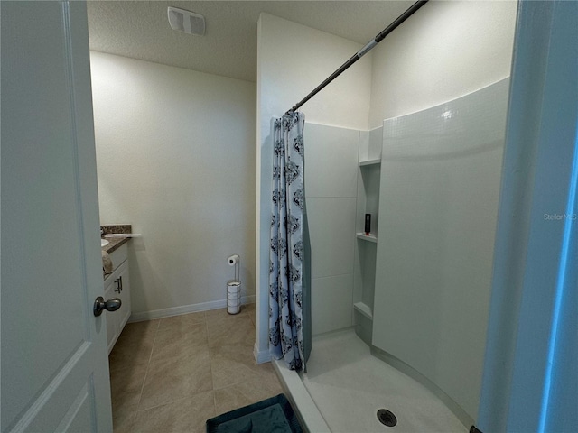 bathroom featuring vanity, a textured ceiling, curtained shower, and tile patterned flooring