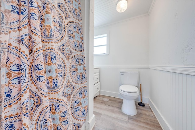 bathroom featuring toilet, ornamental molding, and hardwood / wood-style flooring