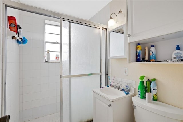 bathroom featuring toilet, a shower with shower door, and vanity