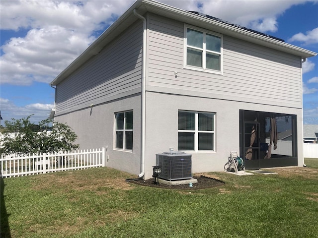 rear view of property featuring a yard and cooling unit