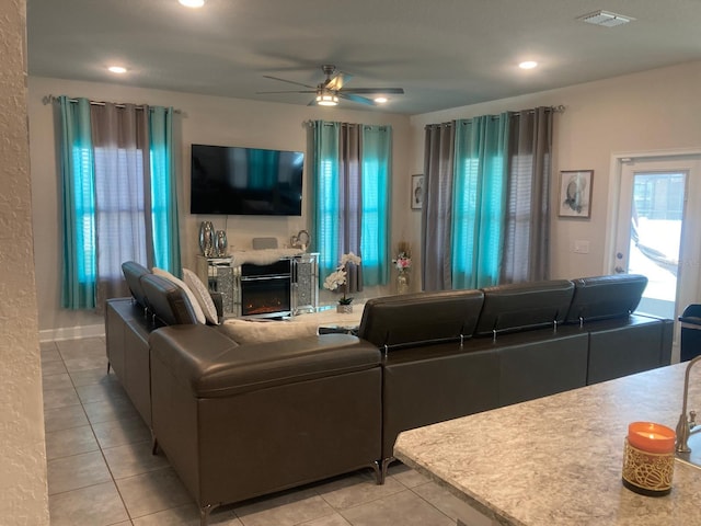 tiled living room featuring ceiling fan and a fireplace