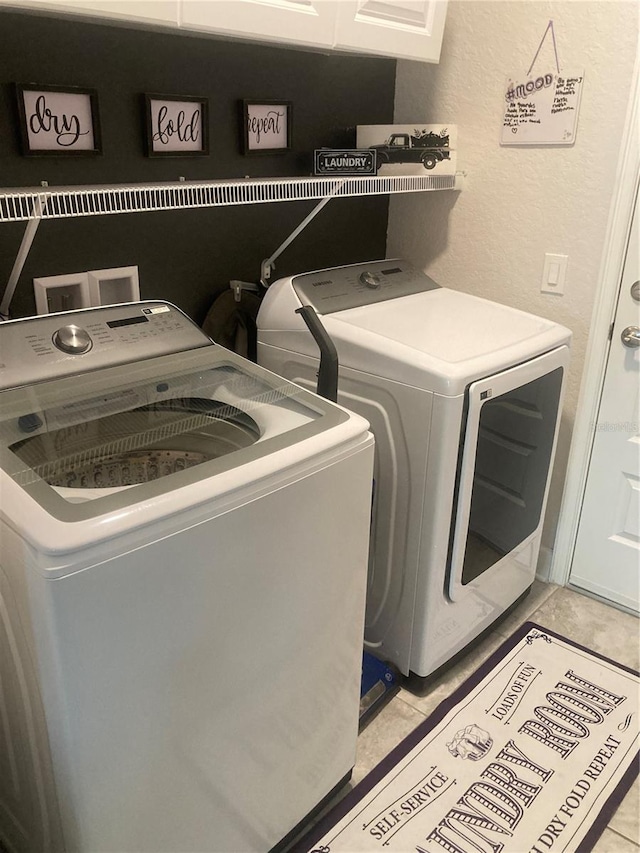 laundry room with cabinets, separate washer and dryer, and light tile patterned floors