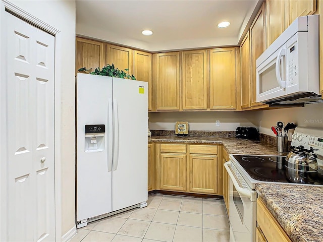 kitchen featuring white appliances, light tile patterned flooring, and dark stone counters