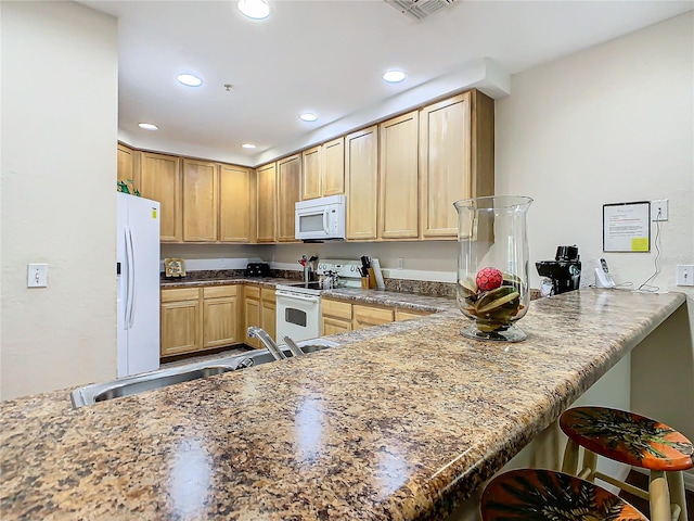 kitchen featuring a kitchen breakfast bar, sink, kitchen peninsula, and white appliances