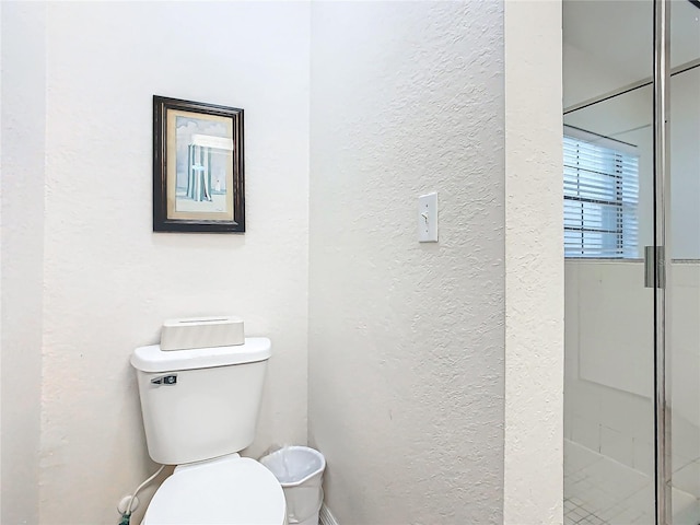 bathroom with toilet and a shower with shower door