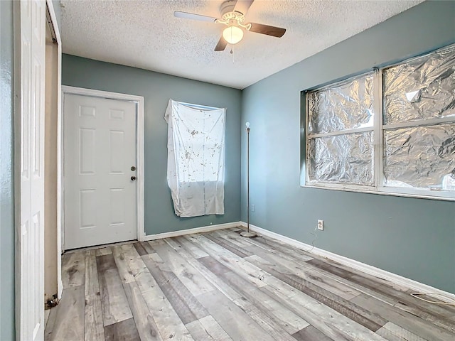 foyer entrance with light hardwood / wood-style floors, a textured ceiling, and ceiling fan