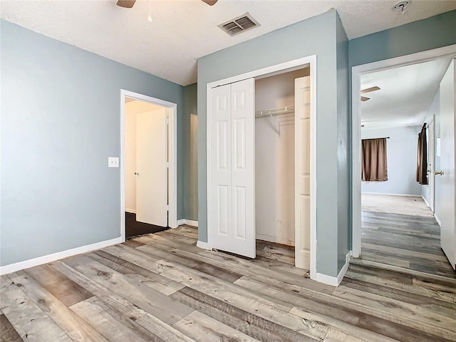 unfurnished bedroom featuring a closet, light hardwood / wood-style floors, and ceiling fan