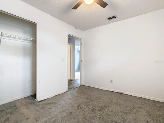 unfurnished bedroom with a textured ceiling, carpet flooring, a closet, and ceiling fan