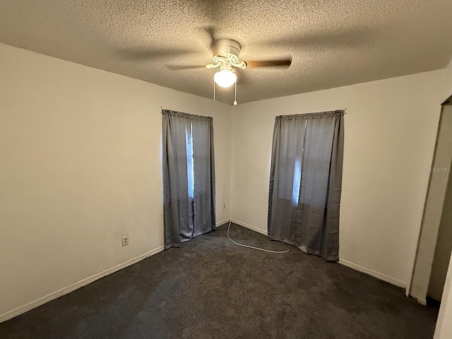 unfurnished bedroom with ceiling fan, a textured ceiling, dark carpet, and baseboards