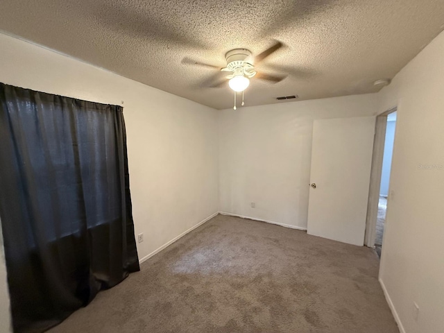 carpeted spare room featuring visible vents, ceiling fan, and a textured ceiling