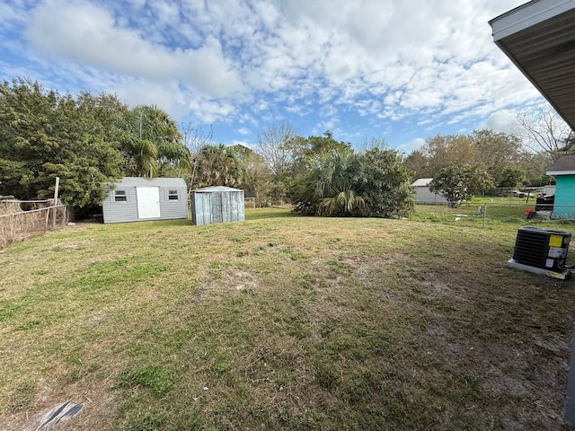 view of yard featuring a fenced backyard, an outdoor structure, central AC unit, and a shed