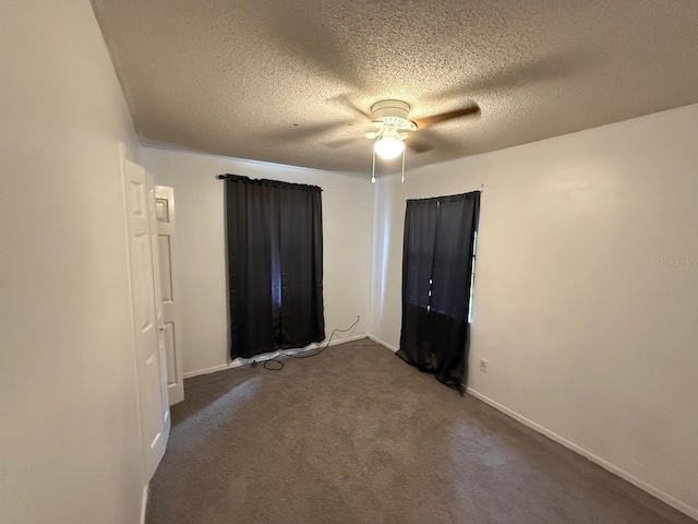 unfurnished room featuring baseboards, dark colored carpet, and a textured ceiling