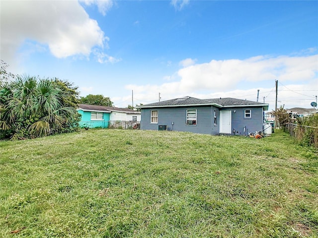 rear view of property featuring a yard, central AC, and fence