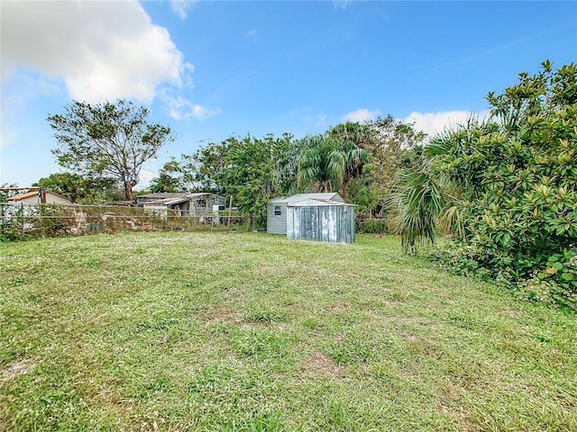 view of yard with fence, a storage unit, and an outdoor structure