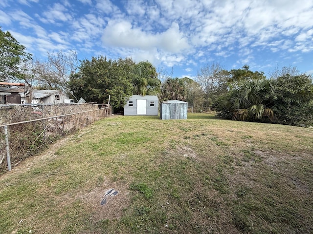 view of yard with a shed, fence, and an outdoor structure