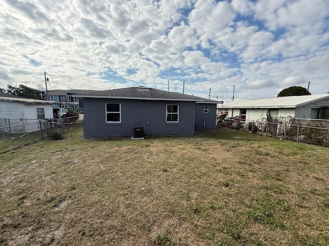 back of house featuring a fenced backyard, central AC unit, and a yard