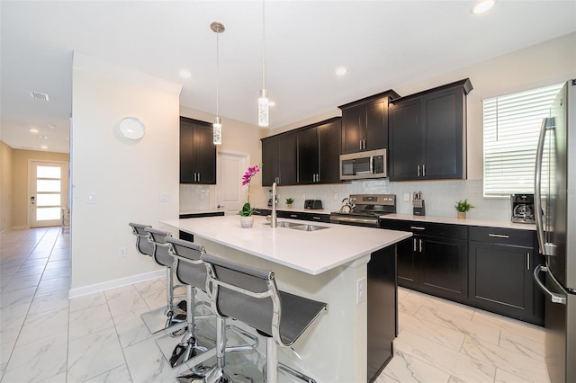 kitchen with appliances with stainless steel finishes, tasteful backsplash, sink, and pendant lighting