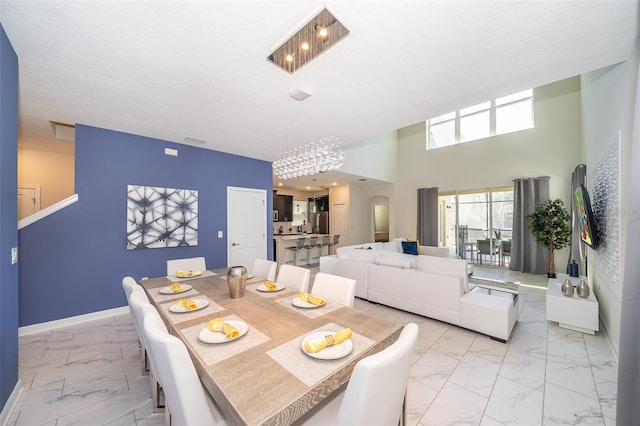 dining area with a high ceiling, a textured ceiling, and an inviting chandelier