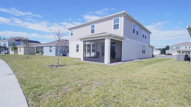 back of house featuring a lawn, a sunroom, and central AC