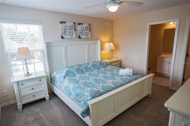 bedroom featuring dark carpet, connected bathroom, a textured ceiling, and ceiling fan