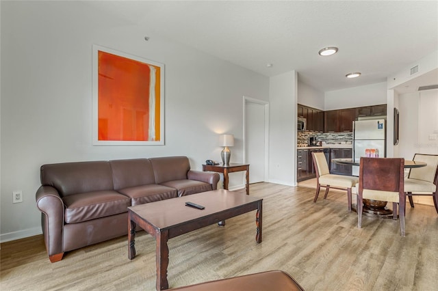 living room with baseboards, visible vents, and light wood-style floors
