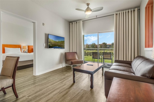 living room featuring wood finished floors, ceiling fan, and baseboards