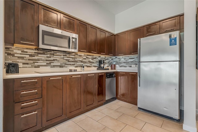 kitchen with light tile patterned floors, decorative backsplash, stainless steel appliances, dark brown cabinets, and light countertops