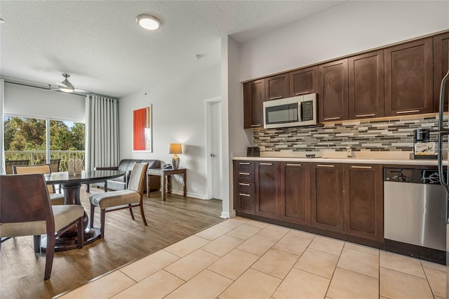 kitchen featuring a textured ceiling, light hardwood / wood-style floors, stainless steel appliances, dark brown cabinetry, and ceiling fan