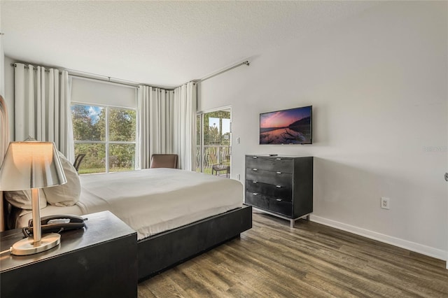 bedroom featuring baseboards, access to exterior, a textured ceiling, and wood finished floors