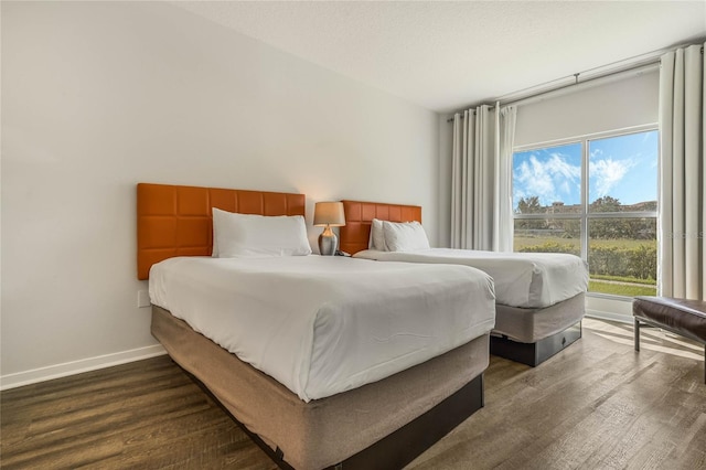 bedroom featuring baseboards and dark wood-type flooring