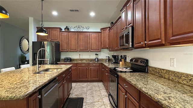 kitchen featuring light stone countertops, sink, an island with sink, stainless steel appliances, and pendant lighting