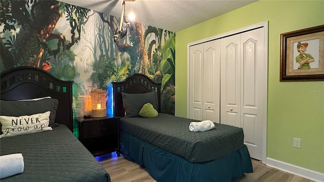 bedroom with light hardwood / wood-style floors, a textured ceiling, and a closet