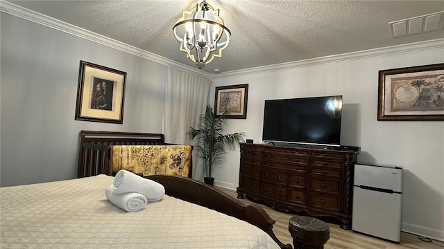 bedroom with a textured ceiling, white fridge, crown molding, a notable chandelier, and light hardwood / wood-style flooring