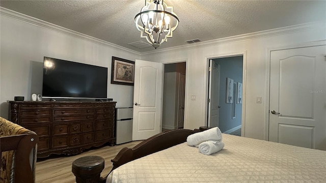 bedroom featuring light hardwood / wood-style flooring, ornamental molding, a chandelier, and a textured ceiling