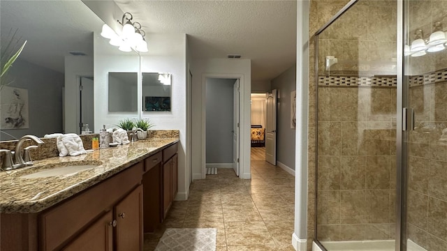 bathroom featuring vanity, tile patterned floors, a textured ceiling, and a shower with shower door